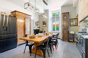 Une cuisine avec une table en bois, des chaises noires, un réfrigérateur et une cuisinière.