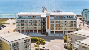 A multi-story hotel with a central staircase, balconies, and a view of the ocean. - Seaside Tranquility|North Pier Ocean Villa+Pool| (Carolina Beach)