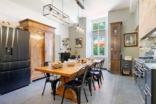 A kitchen with a wooden table, black chairs, a refrigerator, and a stove.