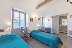 Une chambre avec deux lits, une chaise, un bureau, une lampe et une fenĂȘtre.