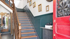 A staircase with wooden balusters and a red door with a decorative leaf pattern.