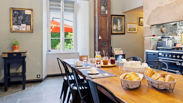 A dining area with a wooden table, chairs, and a window with a view of greenery.