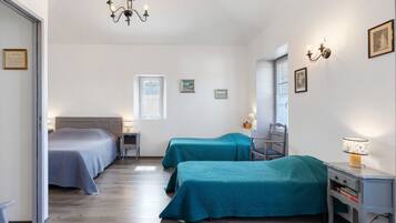 A bedroom with two beds, a desk, a chair, a lamp, and a chandelier.