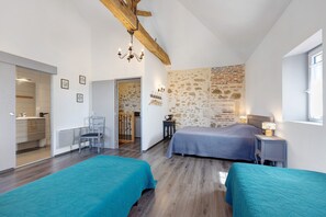 Ein Schlafzimmer mit zwei Betten, einer Steinwand, einem Holzbalken an der Decke und einem Fenster.