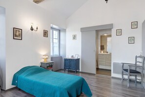 A bedroom with a bed, a desk, a chair, a wardrobe, and a window.