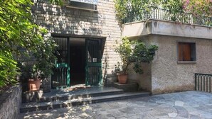 Un edificio de piedra con puerta verde, plantas en macetas y un patio empedrado.