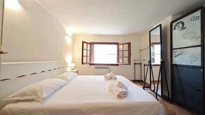Un dormitorio con cama, ventana, radiador y espejo.