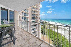 Ein Balkon mit Blick auf einen Strand und ein mehrstöckiges Gebäude.
