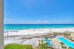 Ein Strandresort mit Pool, Strandliegen und Sonnenschirmen.