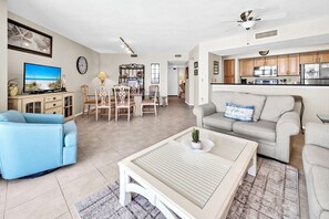 Ein Wohnzimmer mit Fernseher, Sofa, Couchtisch und Essbereich mit Stühlen.