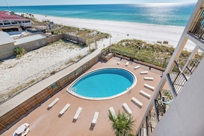 Ein Swimmingpool mit Liegestühlen, Blick auf den Strand und ein Gebäude mit rotem Dach.
