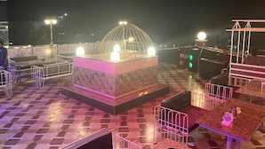 Terraza en la azotea con un área de estar central, mesas y sillas, en un suelo con diseño.