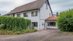 Une maison à deux étages avec une allée en gravier, des murs blancs et un toit recouvert de tuiles.