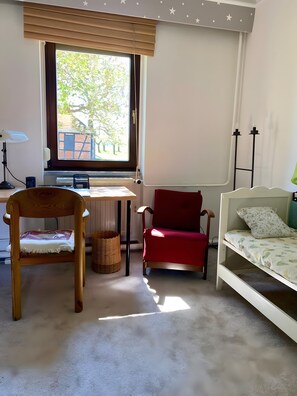 Una habitación con un escritorio, una silla roja, un sofá blanco, una ventana con persianas y una pared decorada con estrellas.