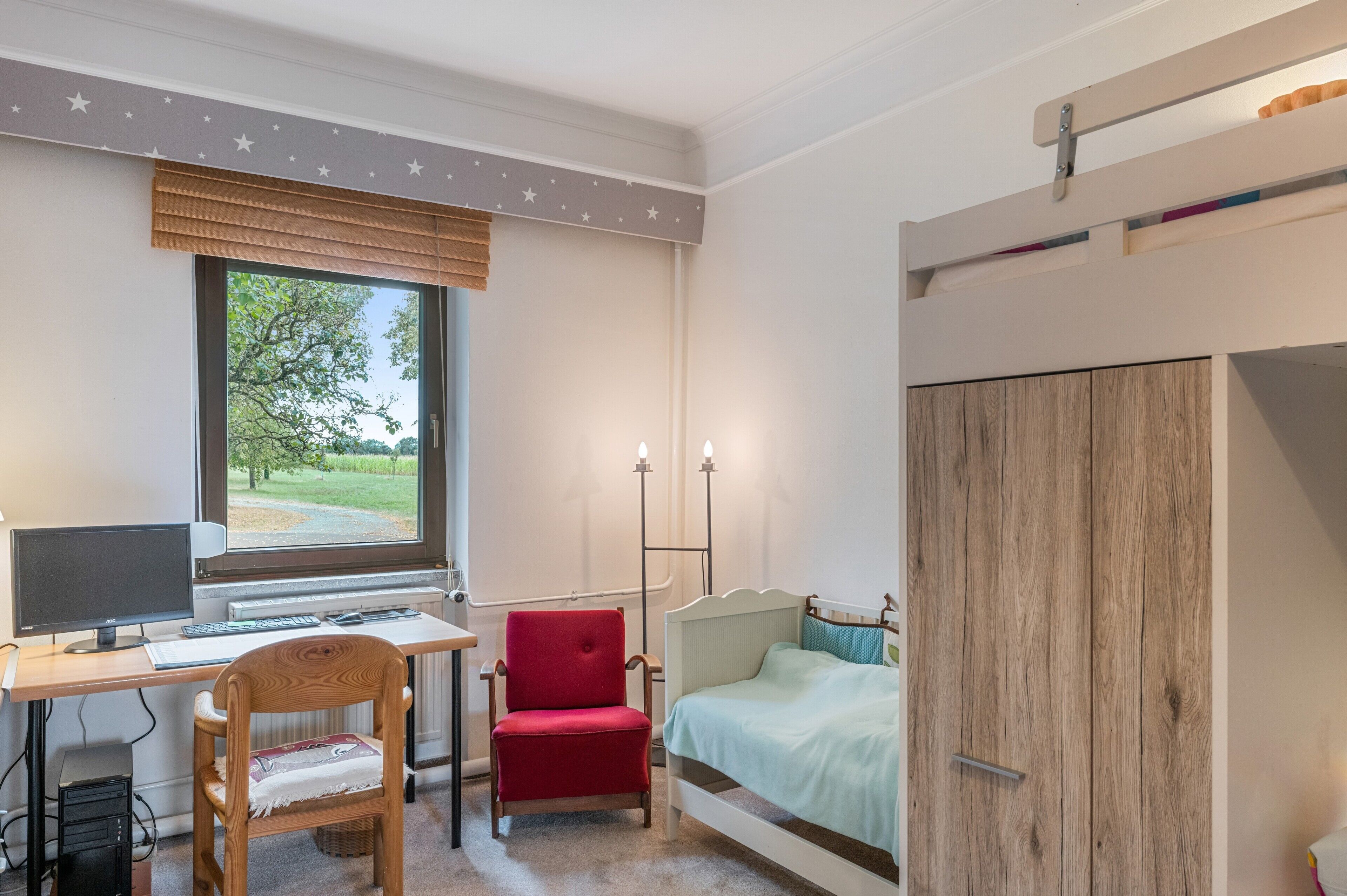 A bedroom with a desk, computer, chair, and bed.