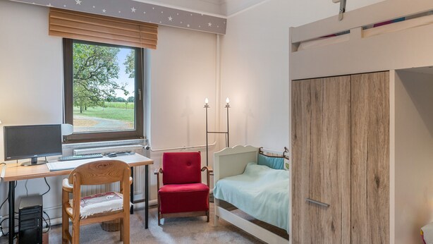 Un dormitorio con escritorio, computadora, silla y cama.