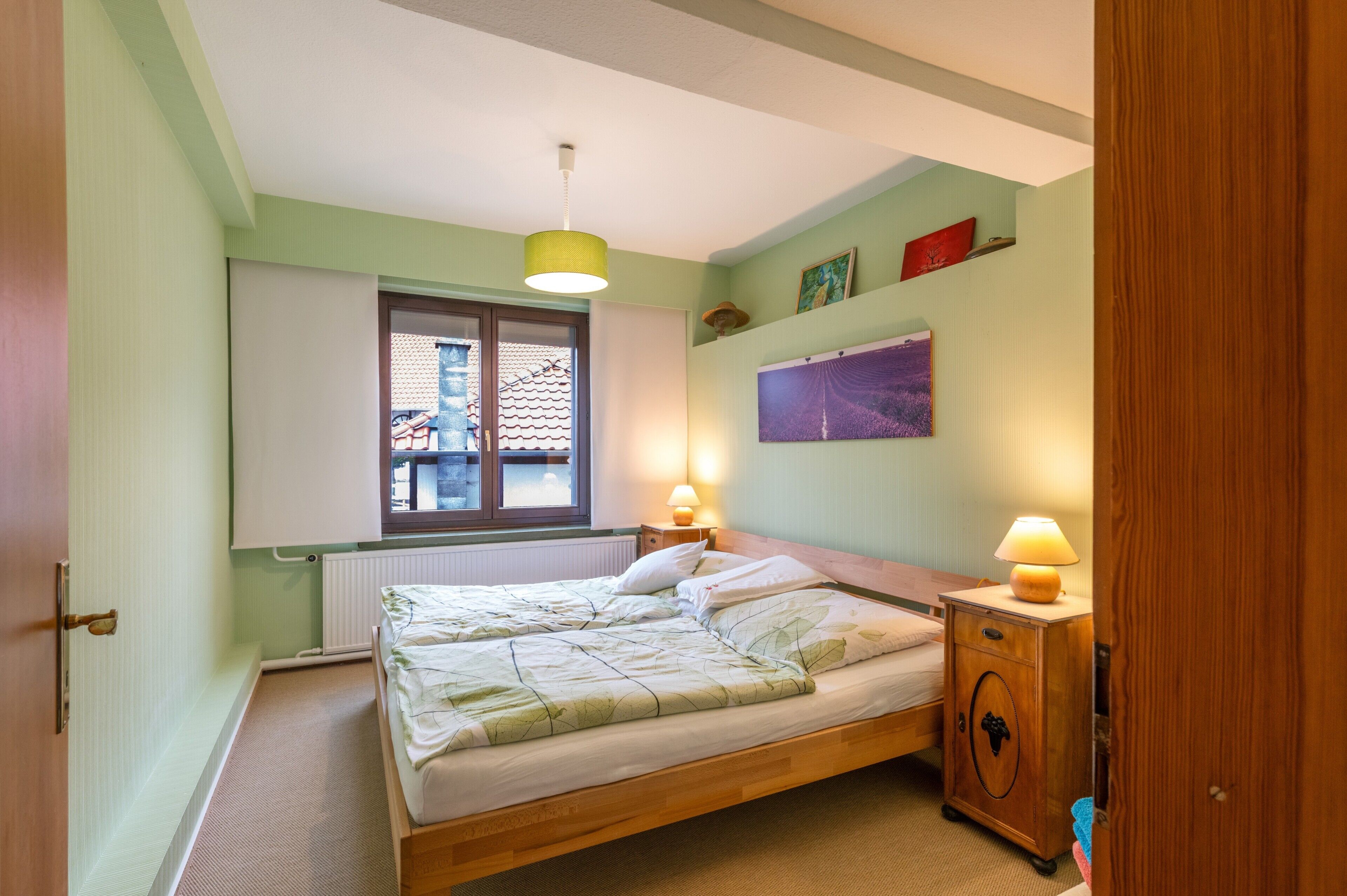 Ein Schlafzimmer mit einem Holzbett, zwei Nachttischlampen, einem Fenster mit Aussicht und einer Heizung.