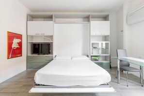 Ein modernes Schlafzimmer mit Bett, Schreibtisch und integrierten Stauraumlösungen.