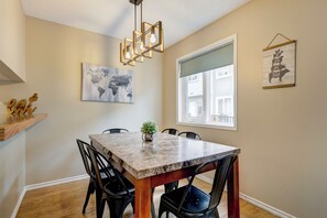 A dining area with a marble table, black chairs, a hanging light fixture, and artwork on the walls. - CRC140: Summer Availability, Perfect for families (Canmore)
