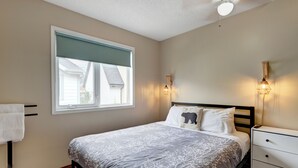 Een slaapkamer met een bed, nachtkastje, lamp en raam.