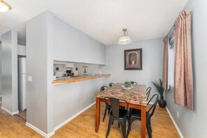 A compact kitchen with a built-in refrigerator, a countertop, and a dining area with a table and chairs.