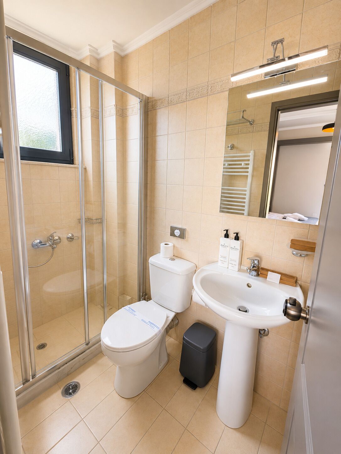 Un baño moderno con ducha envuelta en vidrio, inodoro, lavabo y espejo.