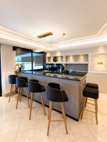 Una cocina moderna con barra, que incluye una isla central, taburetes de bar y electrodomésticos integrados.