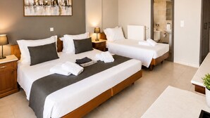Habitación de hotel moderna con dos camas, un cuadro abstracto grande, un escritorio y un baño visible a través de una puerta abierta.