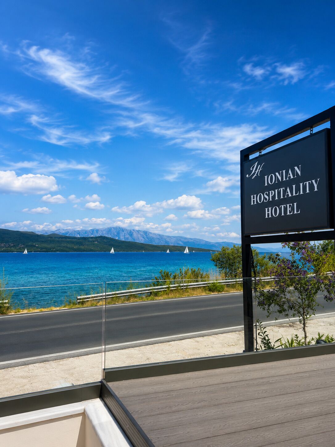 Señal del Hotel Ionian Hospitality con vista a un cuerpo de agua y veleros.