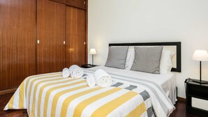 Une chambre d’hôtel avec un lit, une armoire en bois et deux tables de chevet avec des lampes.