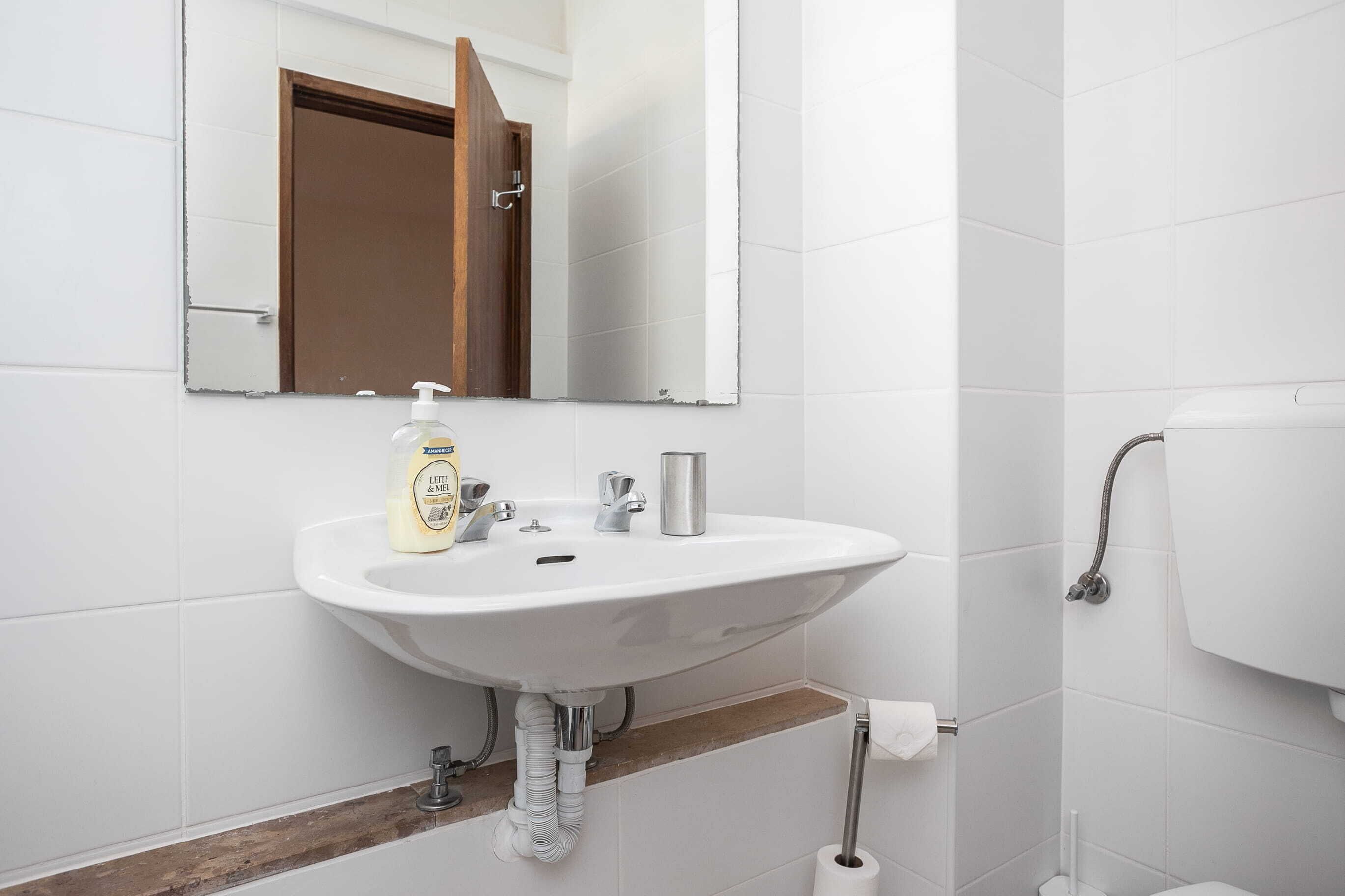 Une salle de bain avec un lavabo blanc, un miroir, des toilettes et une douche.