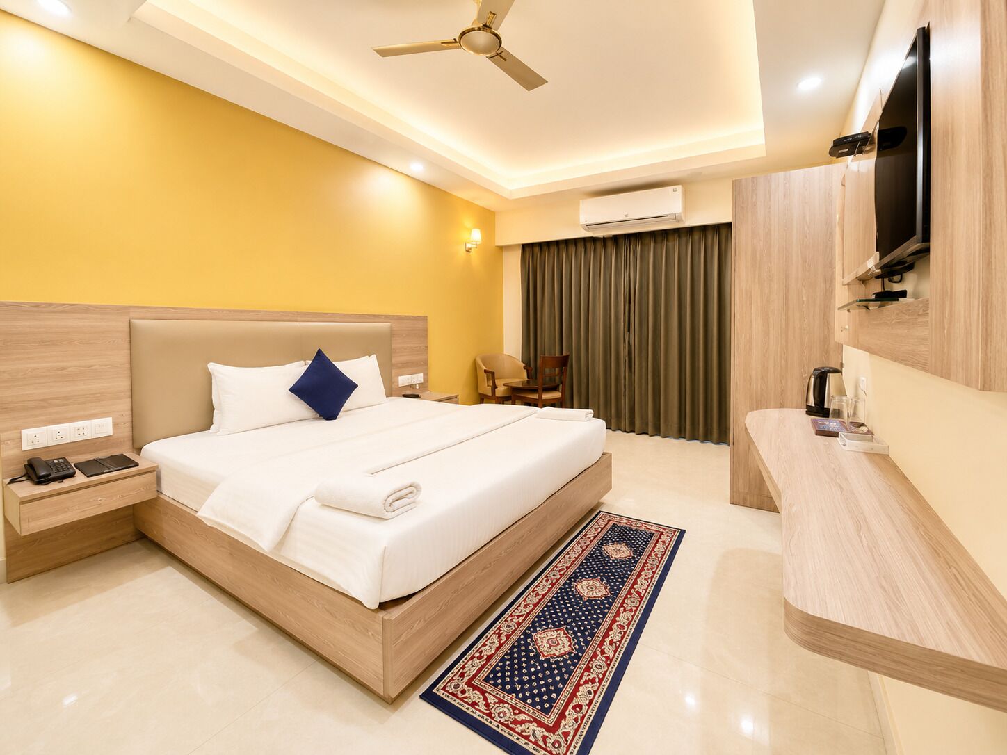 Habitación de hotel con cama, mesita de noche, televisor, aire acondicionado y zona de baño.