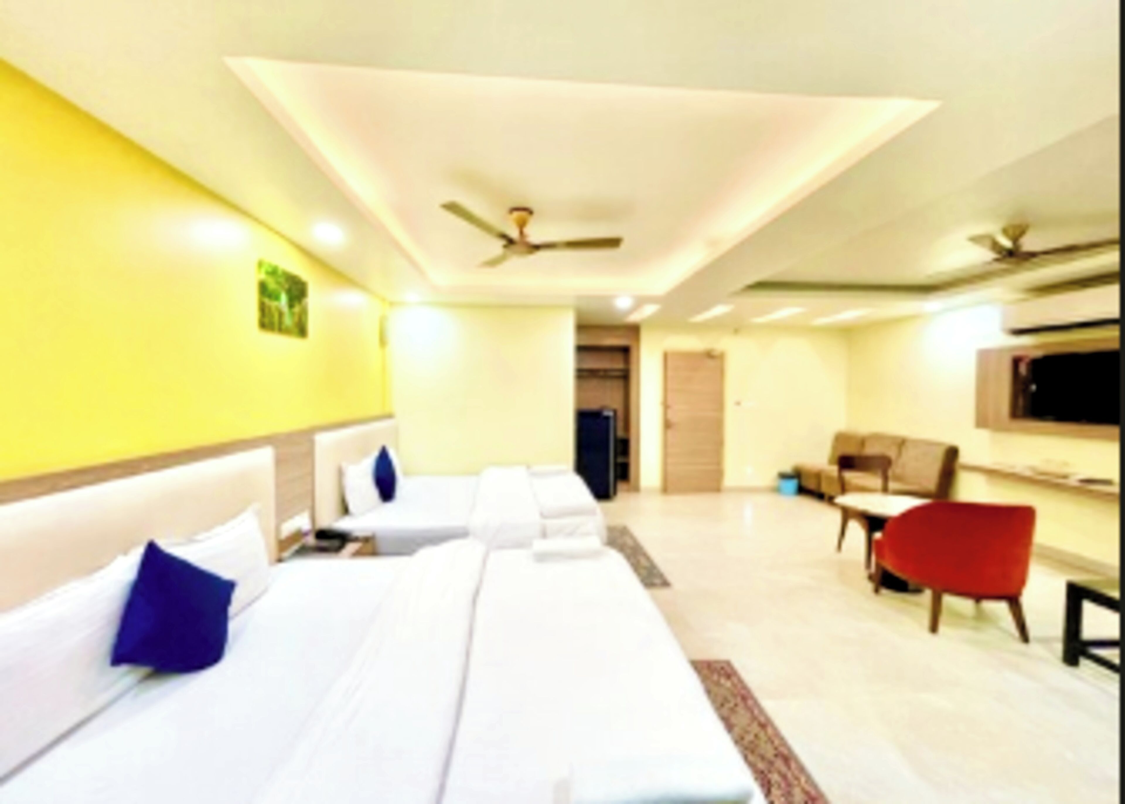 A hotel room with a bed, a desk, a chair, a TV, and a ceiling fan.