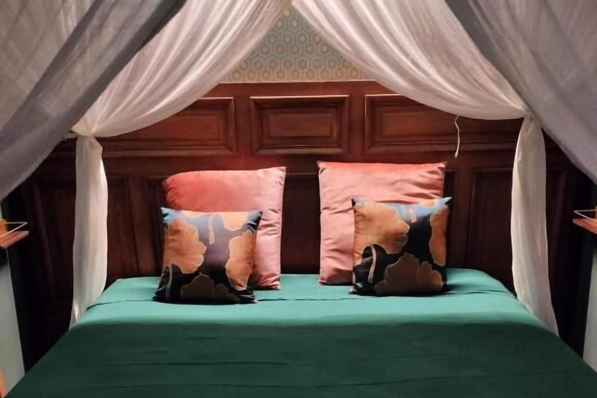 A bed with a green bedspread, two pillows with animal prints, and a canopy.