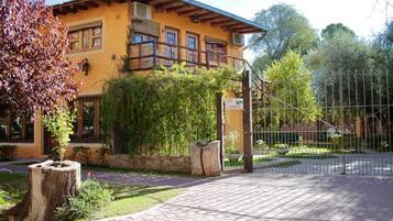 A yellow building with a balcony, a paved entrance, and a fenced garden area.