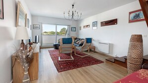 Ein modernes Wohnzimmer mit einer Couch, Sesseln, einer Deckenleuchte und Kunstwerken an den Wänden.