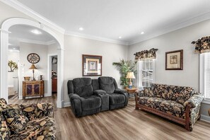 A living room with a dark grey sofa, a floral-patterned sofa, and a wooden cabinet. - Short Walk to Beach, Waterpark and Golf Cart (Myrtle Beach)