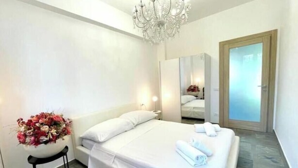 Een hotelkamer met een bed, een stoel, een kroonluchter en een spiegel.