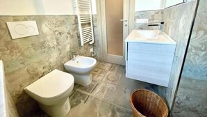 Een badkamer met toilet, bidet en wastafel met spiegel.
