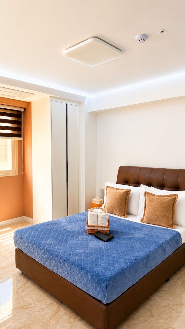 Un dormitorio moderno con una cama grande, un armario, una mesita de noche e iluminación en el techo.