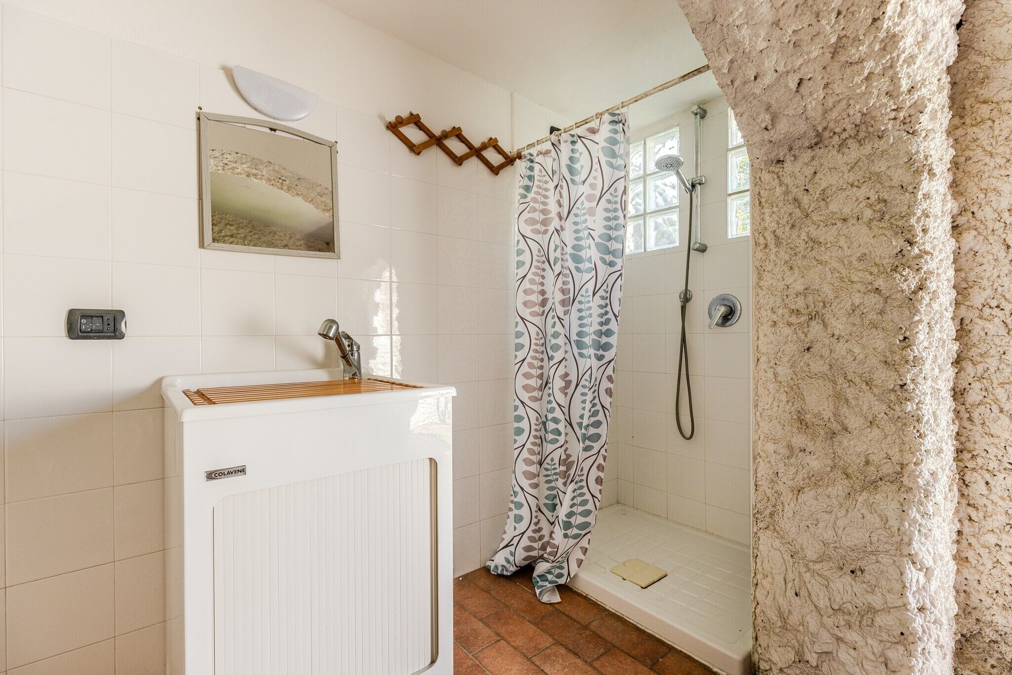 Ein Badezimmer mit Dusche, Waschbecken, Spiegel und Heizkörper.