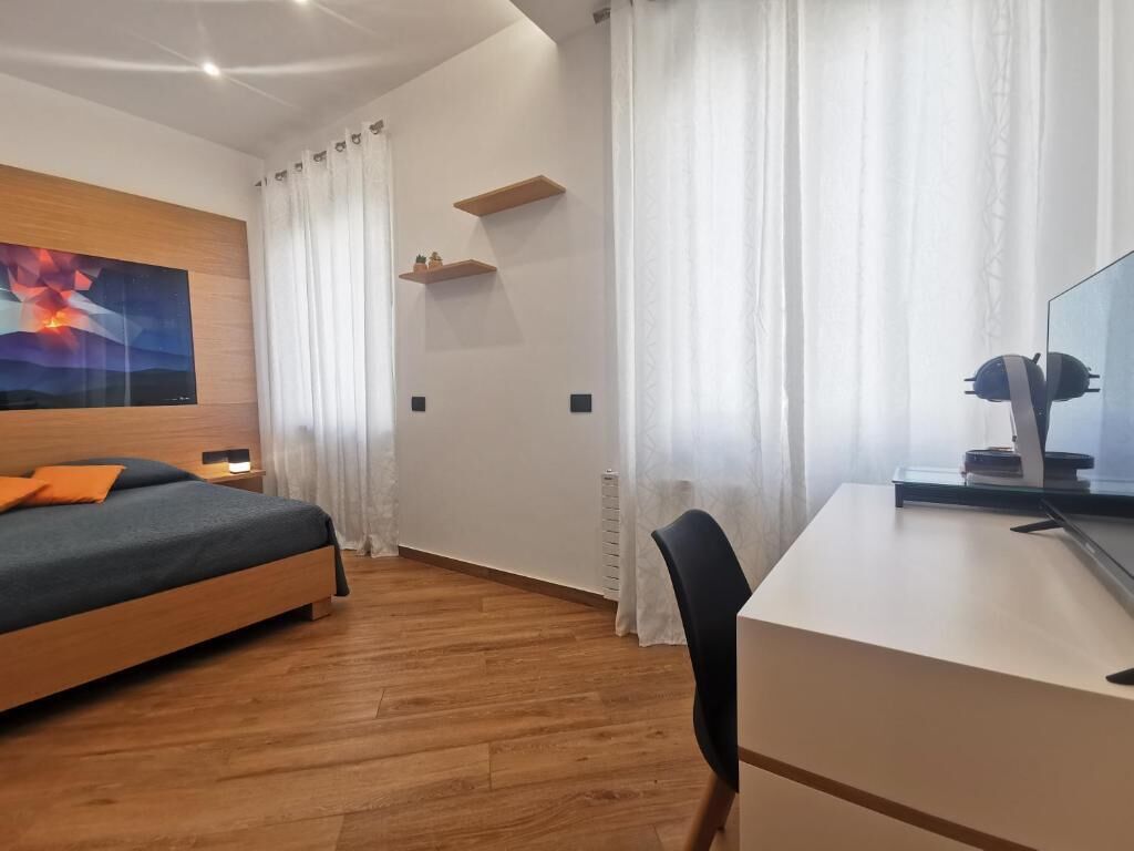 Ein Schlafzimmer mit Bett, Schreibtisch, Stuhl, einem Gemälde und einer Heizung.