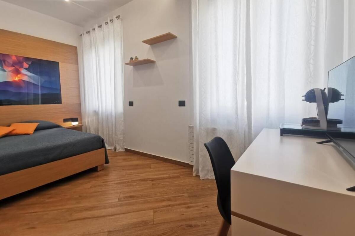 Une chambre à coucher avec un lit, un bureau, une chaise, un tableau et un radiateur.