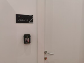 A door with a sign reading 'VULCANO 2' and a keycard reader mounted on the door. - Maqueda Mood (Palermo)