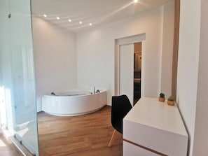 Ein modernes Badezimmer mit freistehender Badewanne, einer Duschkabine aus Glas und Holzboden.