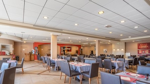A spacious restaurant with multiple tables and chairs, a kitchen area in the background, and a tiled floor. - Balcon privé & vue imprenable sur les collines (Callian)