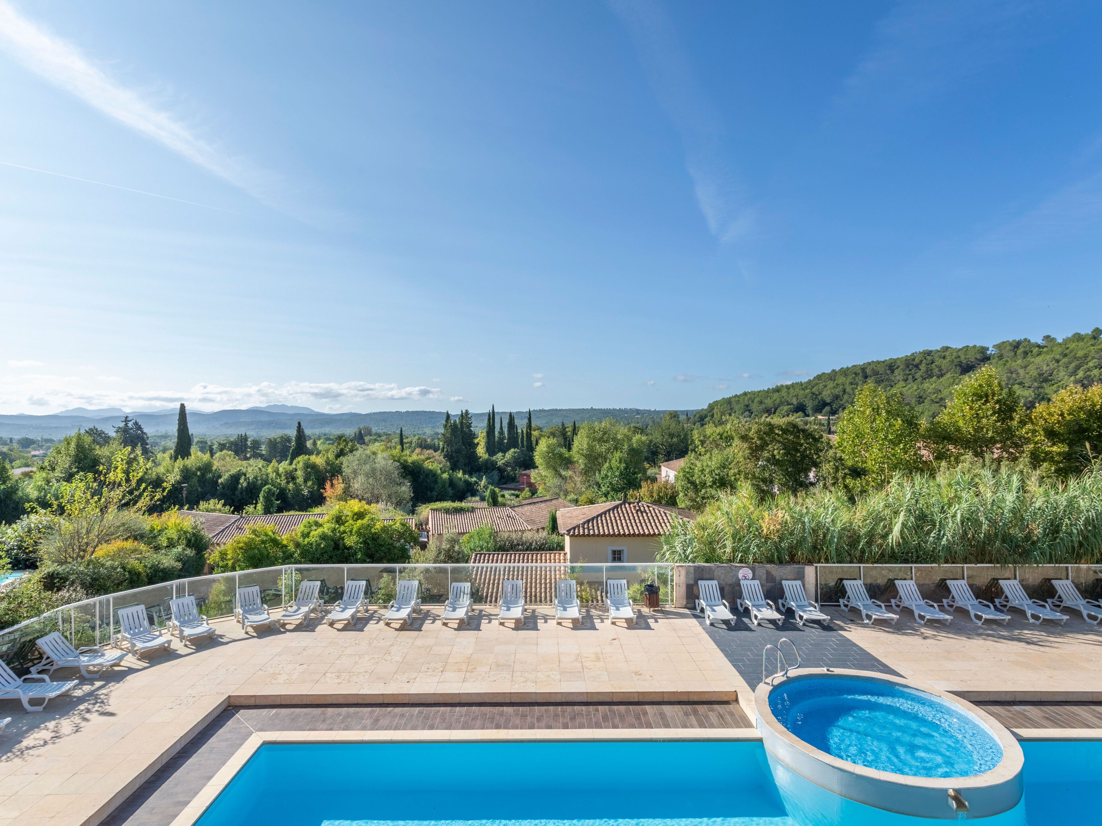 Un espace piscine doté de chaises longues et offrant une vue sur un paysage montagneux.