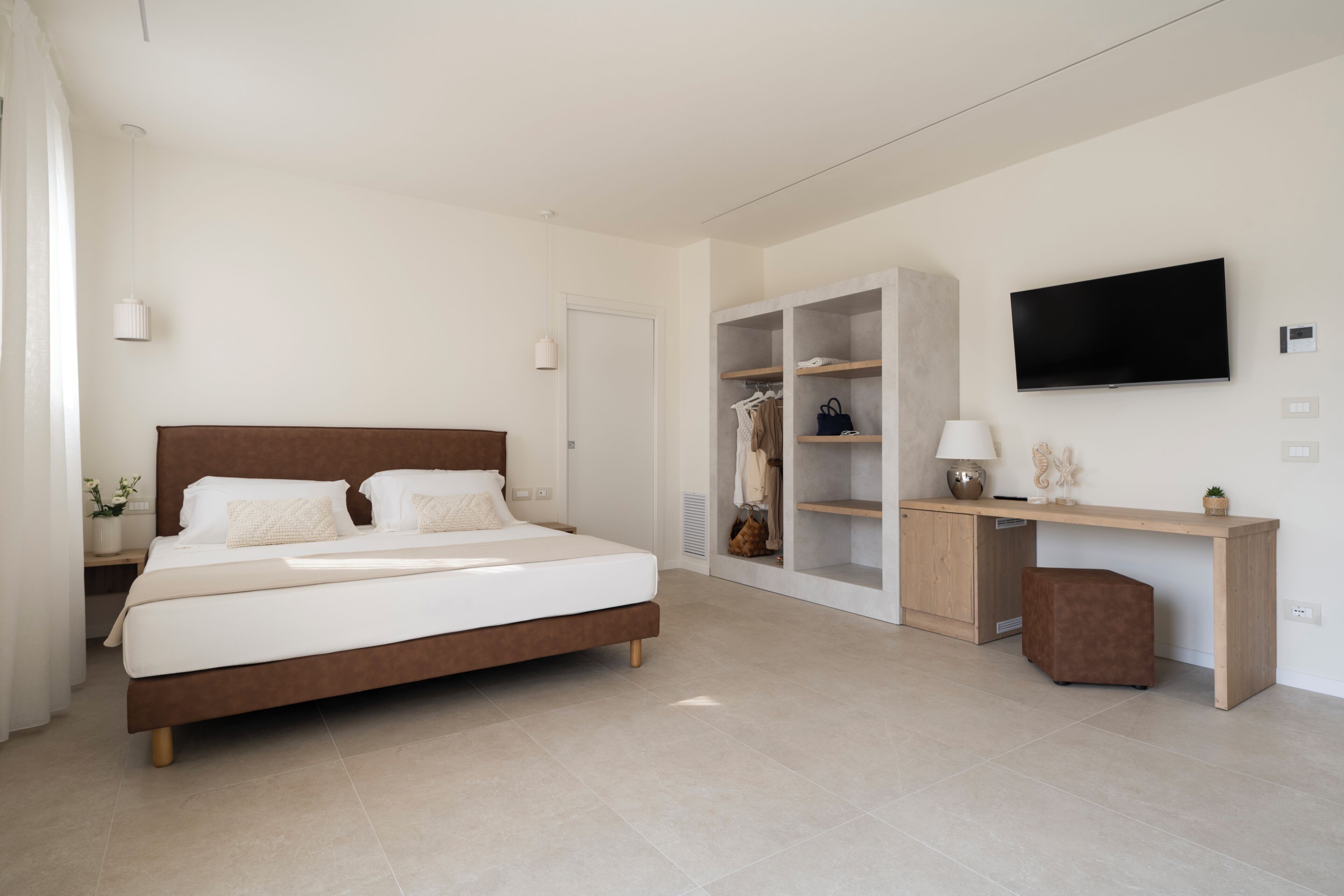 A bedroom with a bed, bedside table, wardrobe, desk, and TV.