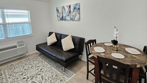 A living room with a black leather sofa, a dining table with chairs, a patterned rug, and abstract wall art. - 4min to World Cup Stadium/Dallas Stadium - 0.9 mile from AT&T Stadium Arlington (Arlington)