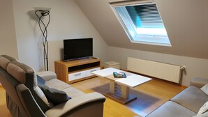 Ein modernes Wohnzimmer im Loft-Stil mit Fernseher, Couchtisch und zwei Sofas.
